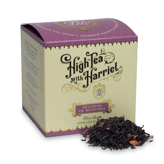 High Tea with Harriet Duchess of Bedford tea in mauve and cream box with loose tea in front featuring rose petals, lavender, and vanilla pieces