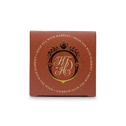 Top view of High Tea with Harriet Morning Tea box with gold crest and branding on copper background