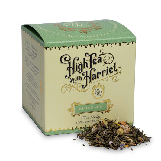 High Tea with Harriet Rising Sun tea in pale green and cream box with loose leaf green tea in front featuring pineapple, petals, and chamomile